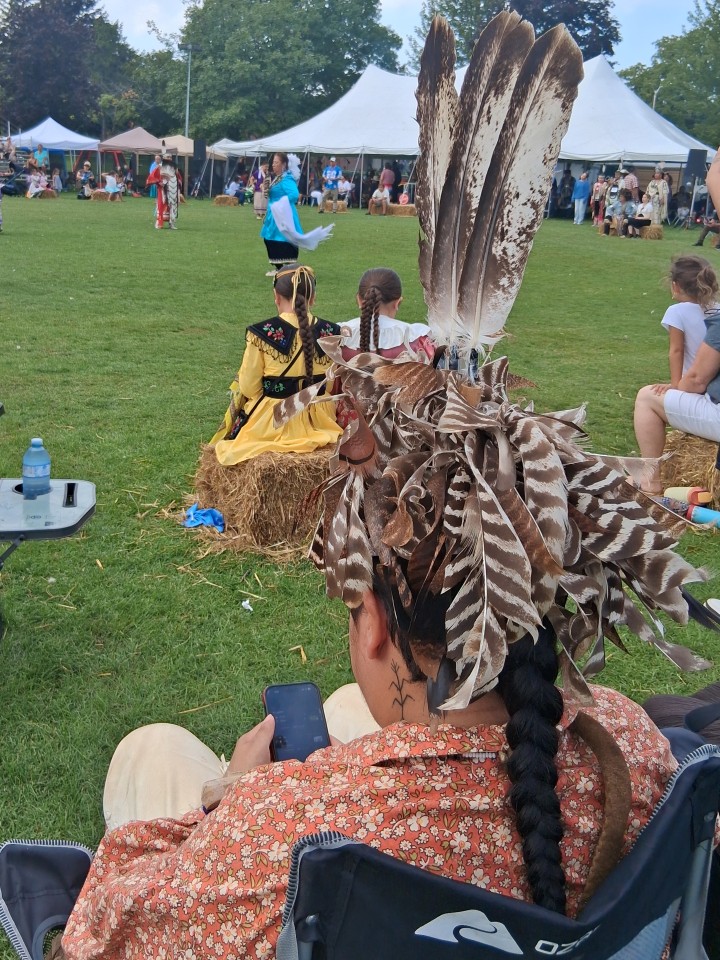 Dancers performing as other participants in regalia watch from the sidelines — Akwesasne International Powwow, Sept. 13, 2026, Lamoureux Park, Cornwall, Ontario, Canada