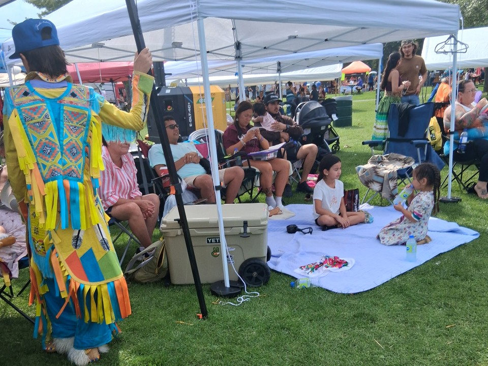 Dancers performing as other participants in regalia watch from the sidelines — Akwesasne International Powwow, Sept. 13, 2026, Lamoureux Park, Cornwall, Ontario, Canada