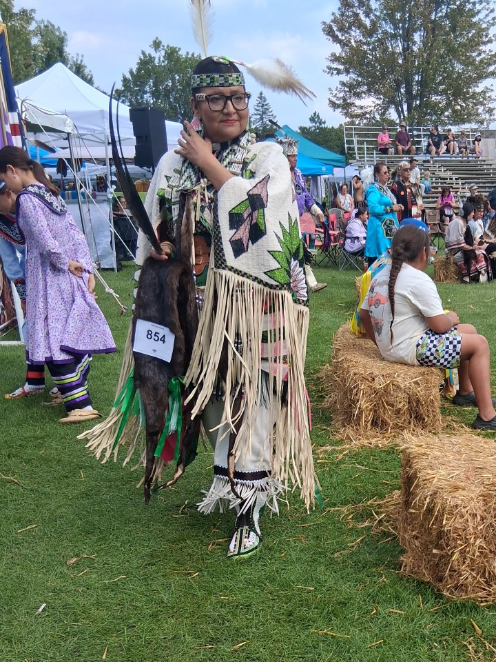 Dancers performing as other participants in regalia watch from the sidelines — Akwesasne International Powwow, Sept. 13, 2026, Lamoureux Park, Cornwall, Ontario, Canada