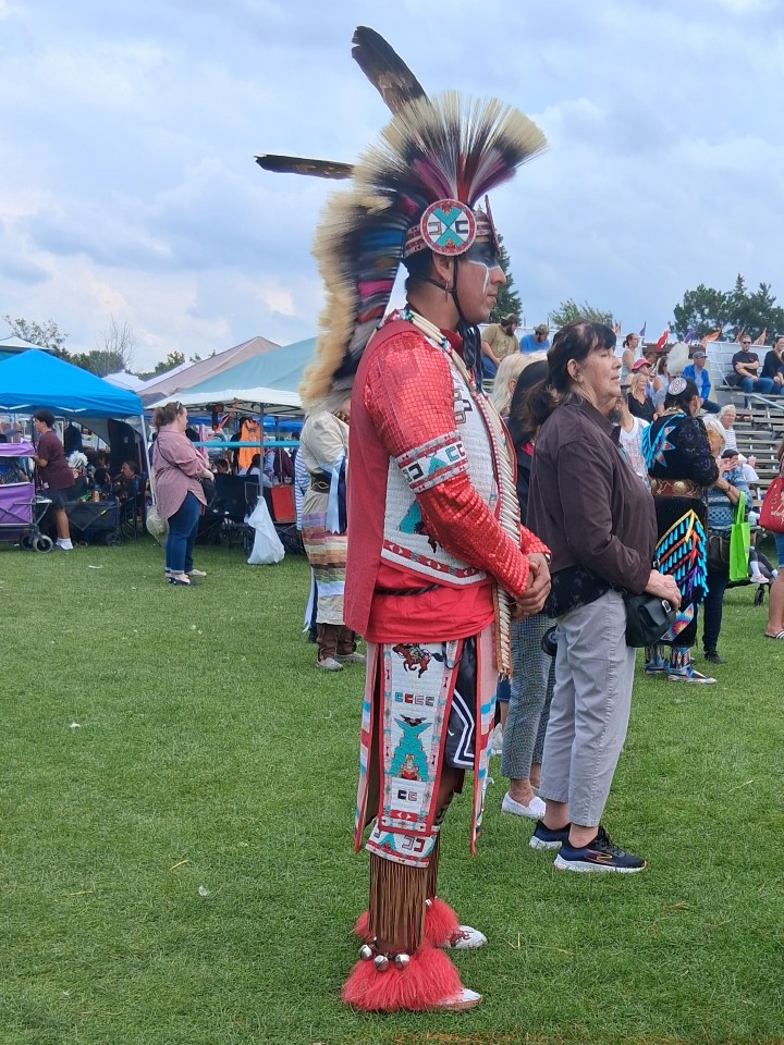 Dancers performing as other participants in regalia watch from the sidelines — Akwesasne International Powwow, Sept. 13, 2026, Lamoureux Park, Cornwall, Ontario, Canada