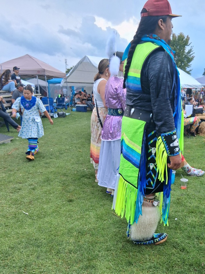 Dancers performing as other participants in regalia watch from the sidelines — Akwesasne International Powwow, Sept. 13, 2026, Lamoureux Park, Cornwall, Ontario, Canada