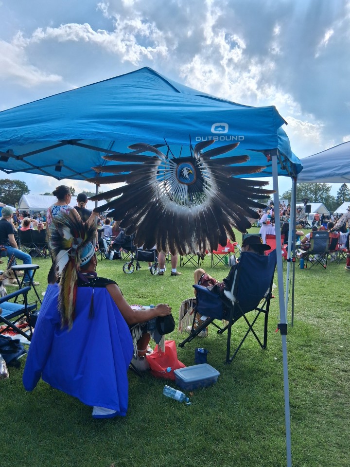 Dancers performing as other participants in regalia watch from the sidelines — Akwesasne International Powwow, Sept. 13, 2026, Lamoureux Park, Cornwall, Ontario, Canada