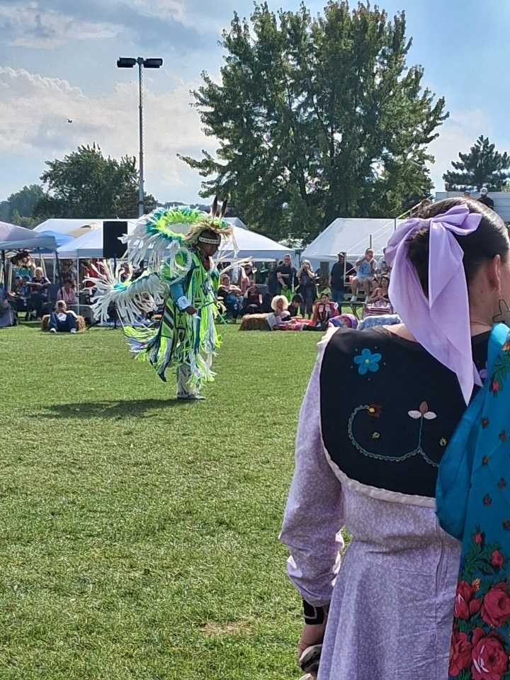 Dancers performing as other participants in regalia watch from the sidelines — Akwesasne International Powwow, Sept. 13, 2026, Lamoureux Park, Cornwall, Ontario, Canada