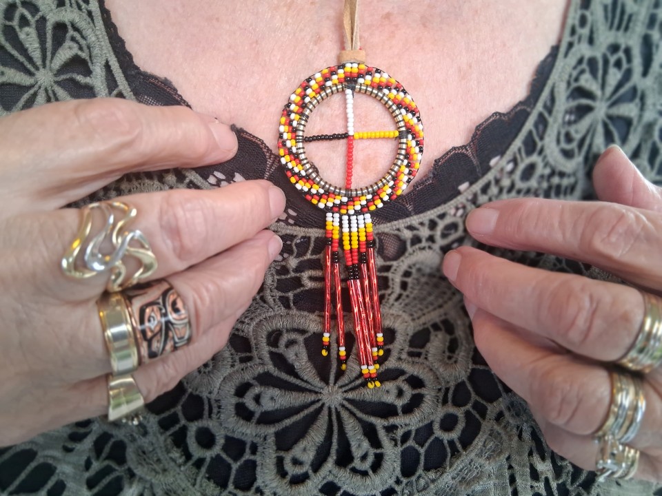 Hand-beaded medicine wheel pendant at the Akwesasne powwow, September 2026
