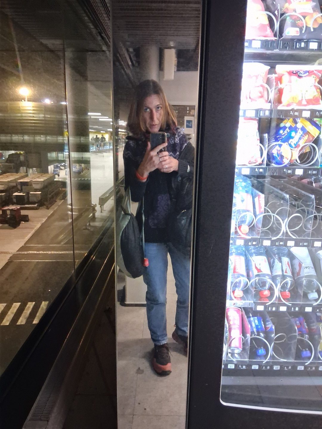 Selfie reflected in a vending machine after the overnight flight — Oct. 18, 2026, Paris Charles de Gaulle Airport, Roissy-en-France, France