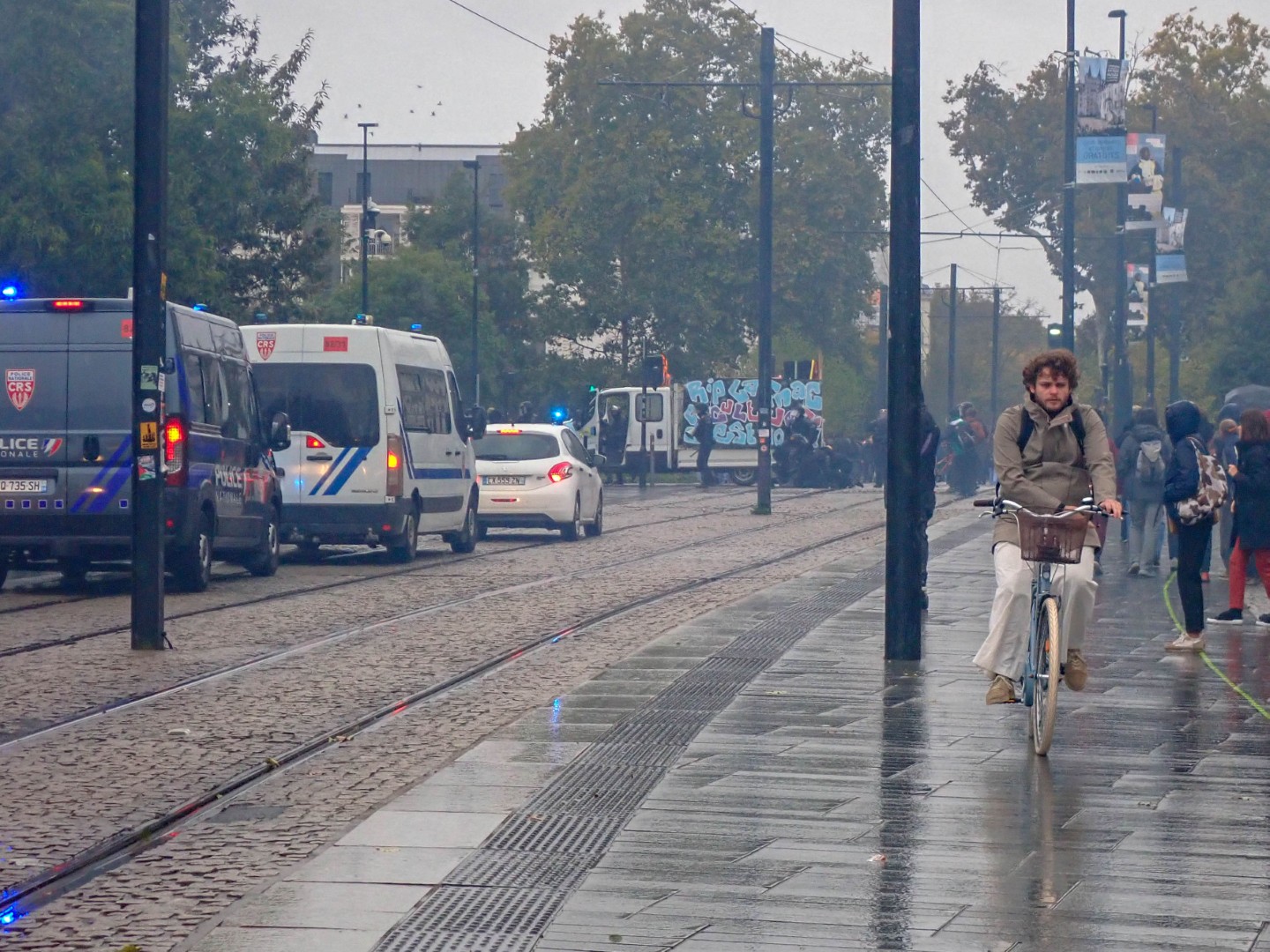CRS vans on the tram tracks as tear gas spreads across the street — Oct. 24, 2026, Cours John F. Kennedy, Nantes, Pays de la Loire, France